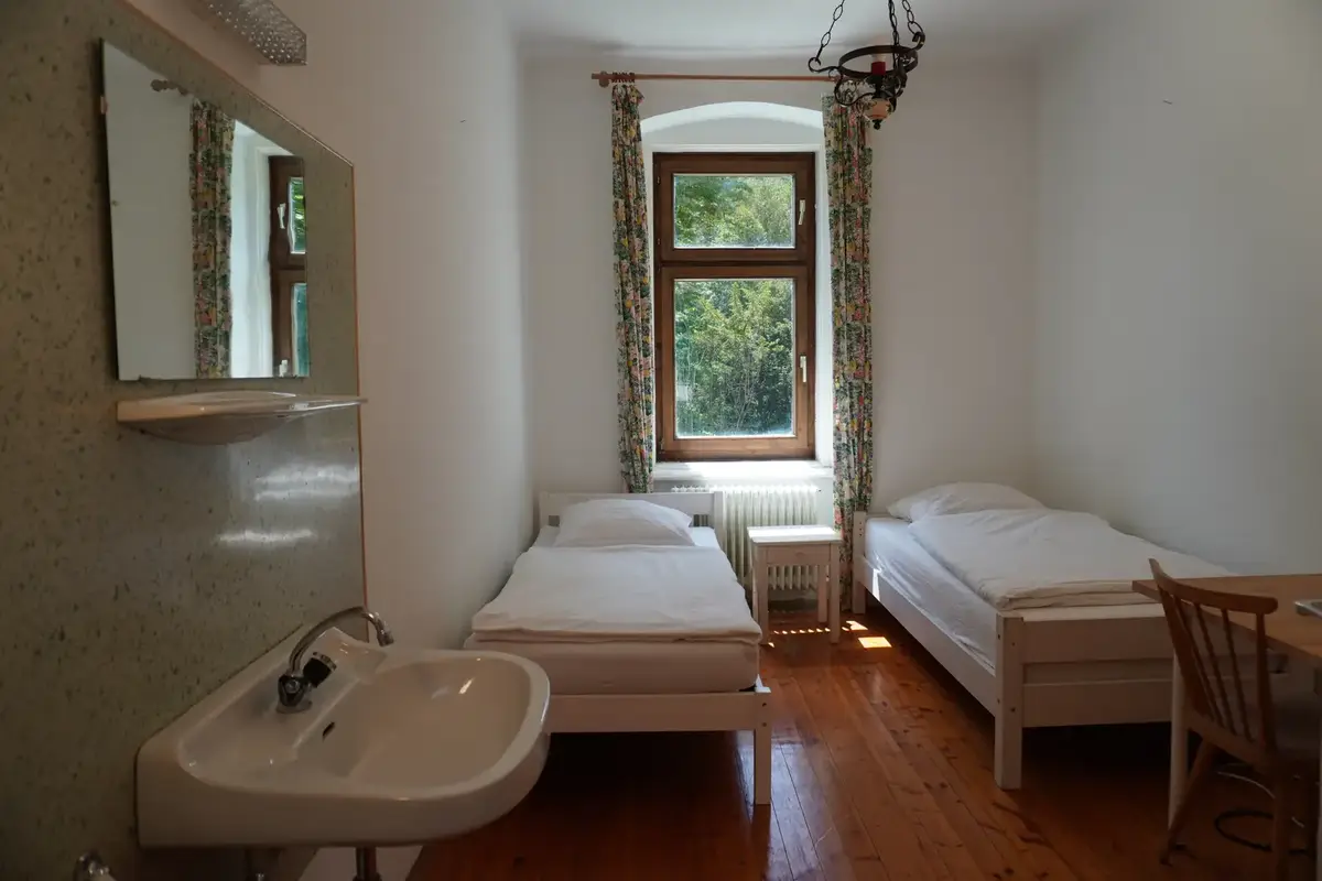 A bright twin room with two beds and a sink